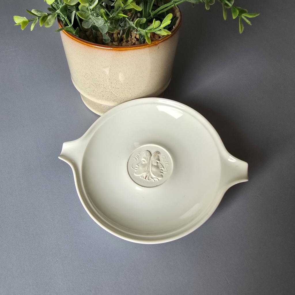 Weißer Porzellan Aschenbecher, Arkadia-Serie von KPM Berlin.
Mittig mit Relief, zu sehen sind zwei Masken